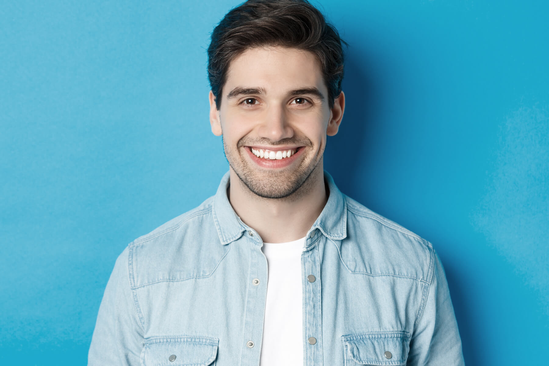 close-up-young-successful-man-smiling-camera-standing-casual-outfit-against-blue-background